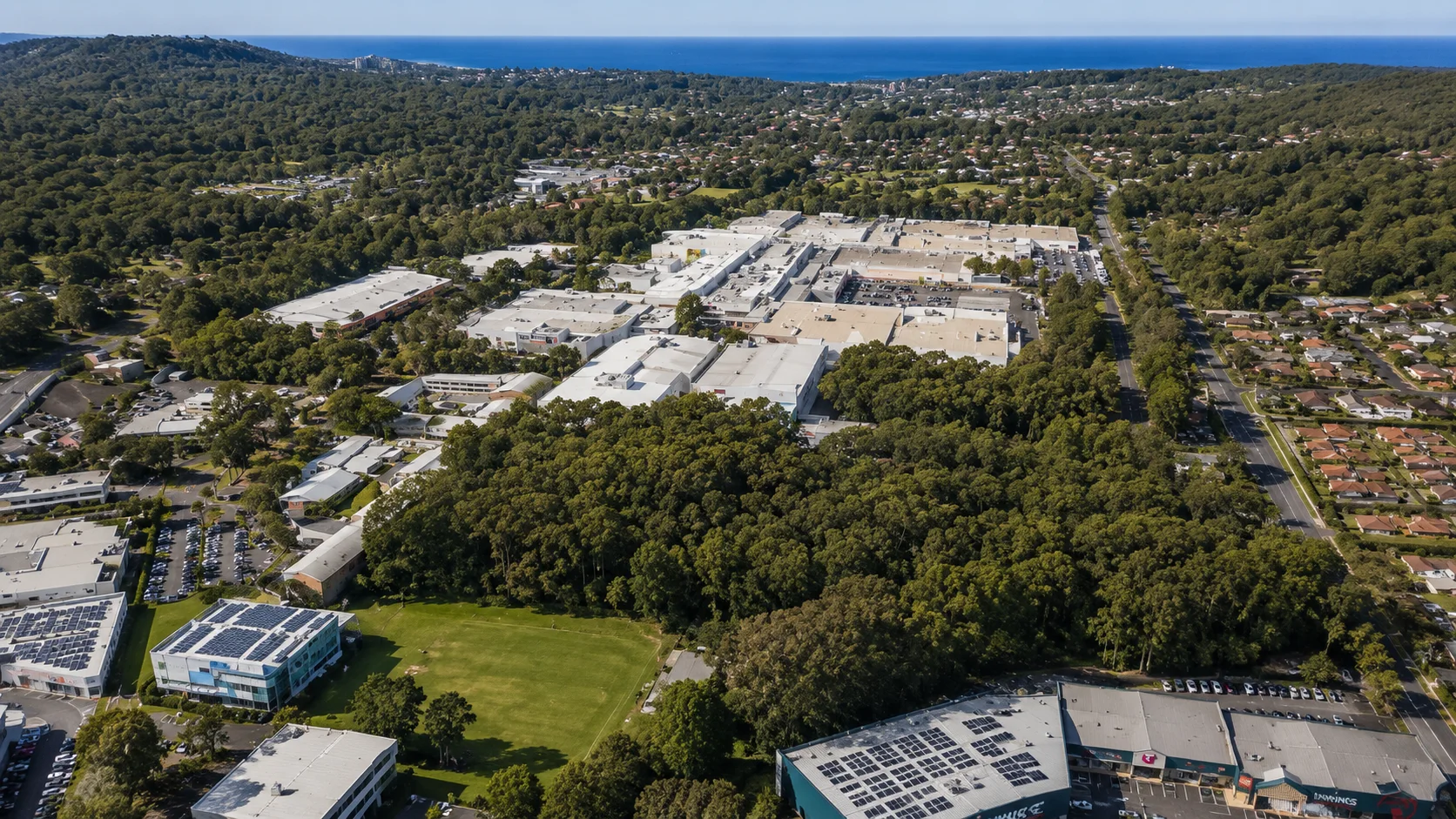 Aerial view over Erina Fair, surrounding business precincts and wooded residential hills towards the coast