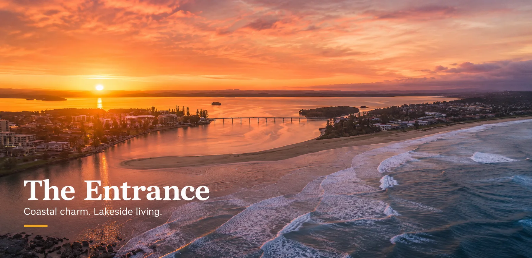 Aerial sunset view of The Entrance where Tuggerah Lake meets the ocean, with the bridge, beach and town