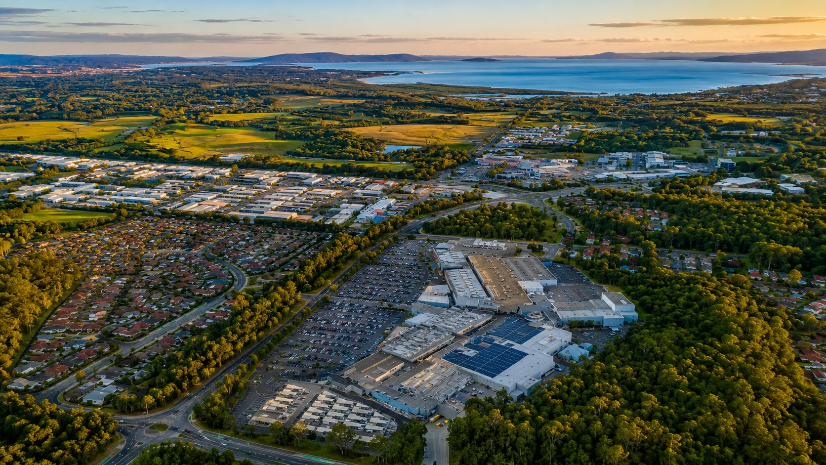 Aerial sunset view over Westfield Tuggerah, surrounding homes and business precincts towards Tuggerah Lake
