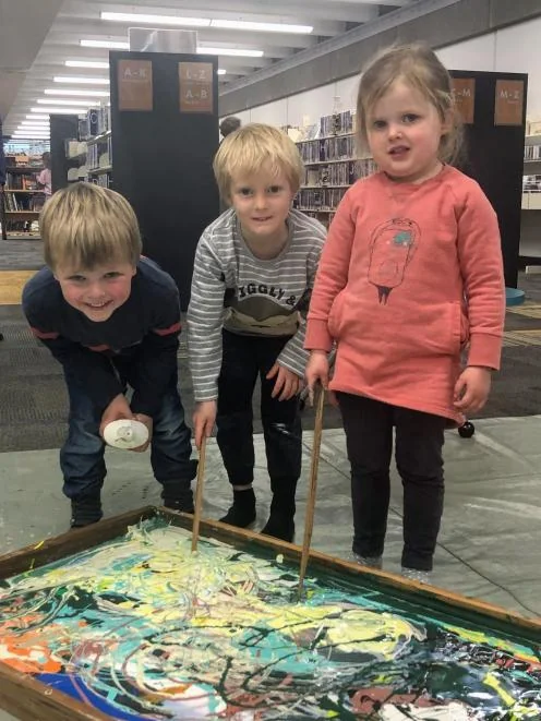 Children making colourful artwork together in a library activity space