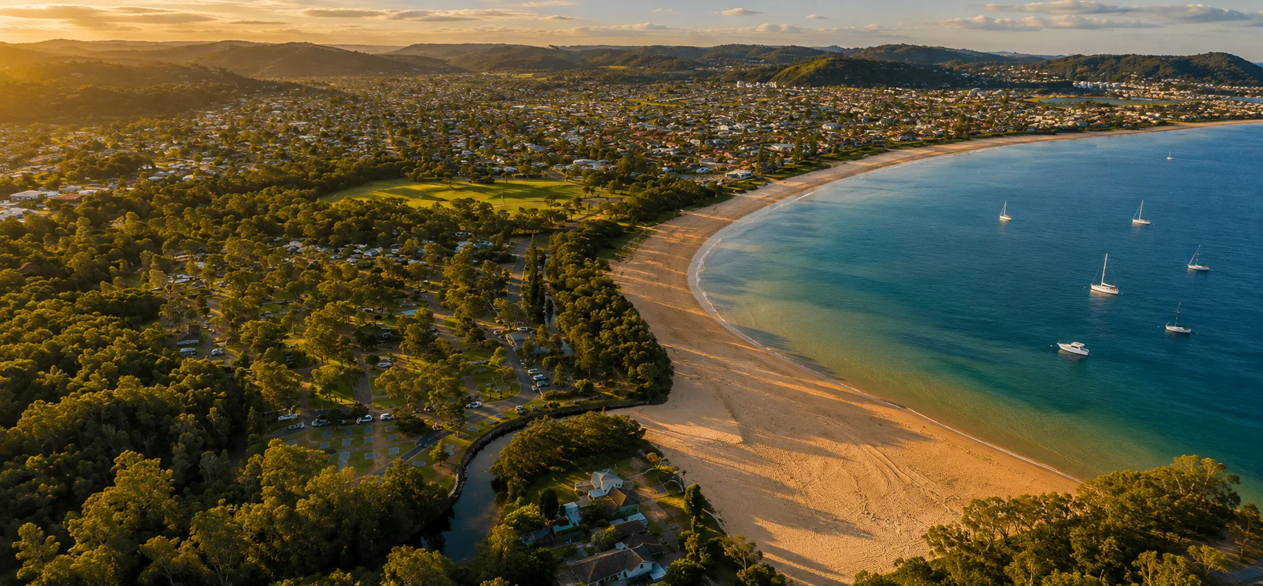 Aerial sunset view along Umina Beach, the beachfront reserve and surrounding suburb