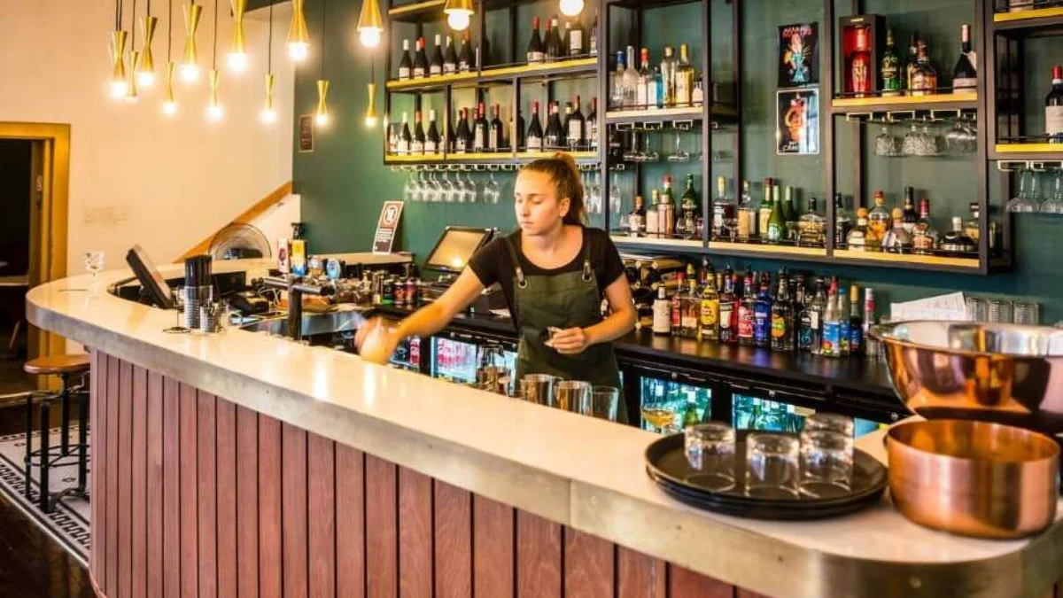 Motel Mezza bar with green shelving, pendant lights and its curved timber counter